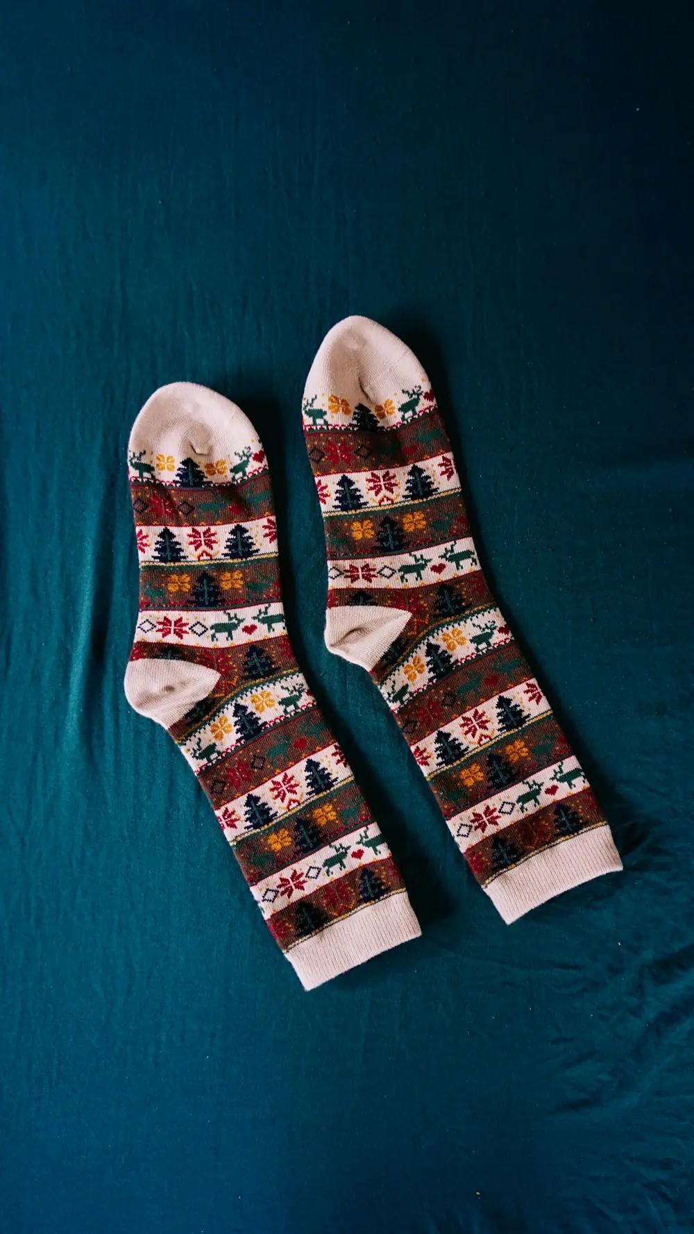 A pair of red, white and navy Christmas socks on a dark teal background